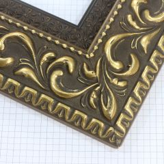 A large, reverse curve profile frame with an intricate leaf design bordered by a geometric outer edge and beaded inner lip.  A dark, matte gold-brown base with gold foil patina for added depth on the topmost points of the design. Strong, solid wood construction.

3.25 " witdth: ideal for large and oversize (extra large) images.